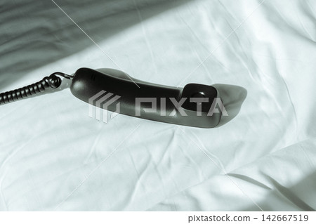 a landline telephone handset on an unmade bed a landline telephone handset on an unmade bed 142667519