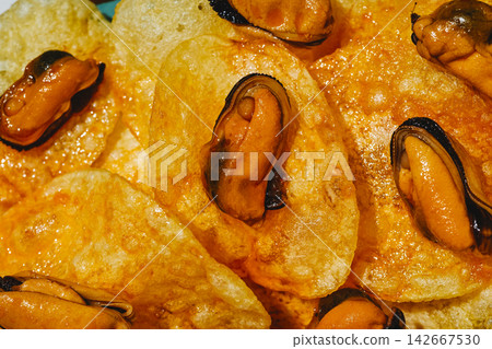 textured close-up of mussels on potato chips 142667530