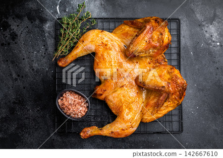 Roasted Spatchcock chicken with herbs and spices, poultry meat on steel rack. black background. top view Roasted Spatchcock chicken with herbs and spices, poultry meat on steel rack. black background. top view 142667610