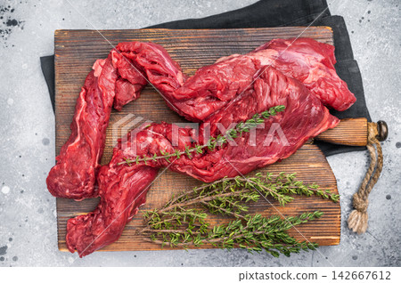 Uncooked Beef Skirt Steak, also name Machete steak, raw meat on cutting board. grey background. top view Uncooked Beef Skirt Steak, also name Machete steak, raw meat on cutting board. grey background. top view 142667612