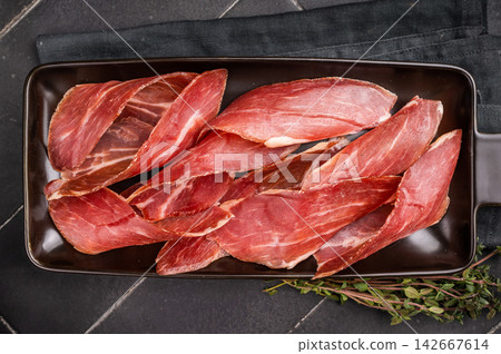 Dry cured and smoked serrano ham, pork meat. black background. top view Dry cured and smoked serrano ham, pork meat. black background. top view 142667614