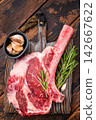 Raw Tomahawk beef steak, fresh black angus ribeye with bone on wooden board. wooden background. top view 142667622