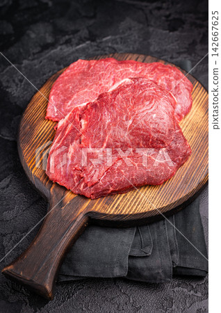 Butcher board with raw beef cheeks, uncooked meat. black background. top view Butcher board with raw beef cheeks, uncooked meat. black background. top view 142667625
