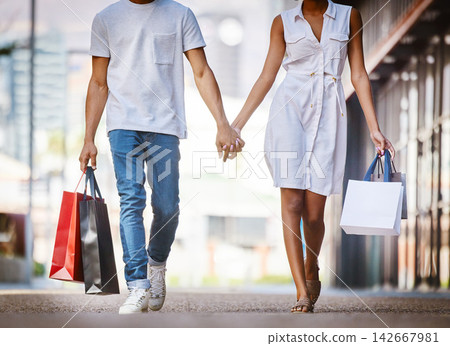 City, shopping and couple walk holding hands with bags from retail, sales and relax on holiday or vacation. Customer, people and travel to mall on date with promo purchase of product or fashion City, shopping and couple walk holding hands with bags from retail, sales and relax on holiday or vacation. Customer, people and travel to mall on date with promo purchase of product or fashion 142667981
