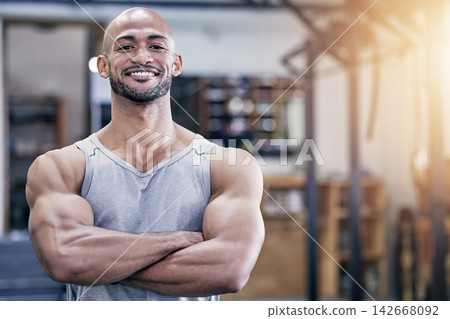 Man, portrait and arms crossed in gym with muscles for training client, strong body and health career. Pride, smile and face of personal trainer in wellness club for workout, exercise and bodybuilder 142668092