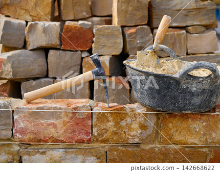 Masonry stone wall construction with tools 142668622