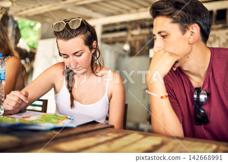 People, friends and restaurant with map for travel, desintation or decision on next route or path. Man, woman or travelers looking at tour guide for location, distance or trip at local indoor cafe People, friends and restaurant with map for travel, desintation or decision on next route or path. Man, woman or travelers looking at tour guide for location, distance or trip at local indoor cafe 142668991
