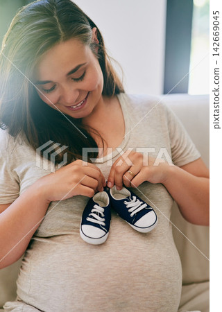 Happy, pregnant woman and shoes on belly in home for reveal of boy gender, journey and experience of pregnancy. Mother to be, holding sneakers and stomach for love or bonding and motherhood with care Happy, pregnant woman and shoes on belly in home for reveal of boy gender, journey and experience of pregnancy. Mother to be, holding sneakers and stomach for love or bonding and motherhood with care 142669045