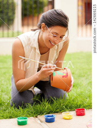 Ceramic, pot and girl painting a craft container for plant in garden with creativity, happiness or hobby. Clay, art and artist with inspiration outdoor with paint brush, decoration or fun project Ceramic, pot and girl painting a craft container for plant in garden with creativity, happiness or hobby. Clay, art and artist with inspiration outdoor with paint brush, decoration or fun project 142669215
