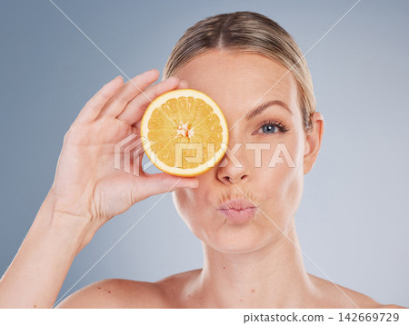 Skincare, orange and portrait of model in studio for facial treatment, natural glow or wellness on gray background. Clean, beauty and hand of woman with kiss lips for vitamin c, eco or dermatology Skincare, orange and portrait of model in studio for facial treatment, natural glow or wellness on gray background. Clean, beauty and hand of woman with kiss lips for vitamin c, eco or dermatology 142669729