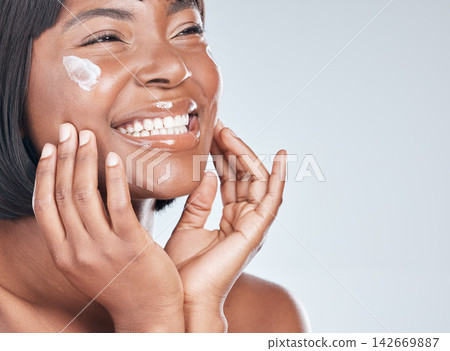 Happy black woman, skincare and facial with cream for beauty or moisturizer on a white studio background. Face of African, female person or model with smile for lotion, cosmetics or healthy skin Happy black woman, skincare and facial with cream for beauty or moisturizer on a white studio background. Face of African, female person or model with smile for lotion, cosmetics or healthy skin 142669887