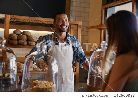 Bakery, happy and man in cafe with customer for serving pastry, cakes and baked foods for small business. Restaurant, coffee shop and waiter or barista by counter for service, help and talk to woman Bakery, happy and man in cafe with customer for serving pastry, cakes and baked foods for small business. Restaurant, coffee shop and waiter or barista by counter for service, help and talk to woman 142669888