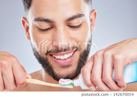 Brushing teeth, toothbrush and man in studio for wellness, fresh breath and oral care on grey background. Toothpaste, smile or model with bamboo product for mouth, cleaning or bacteria prevention Brushing teeth, toothbrush and man in studio for wellness, fresh breath and oral care on grey background. Toothpaste, smile or model with bamboo product for mouth, cleaning or bacteria prevention 142670054
