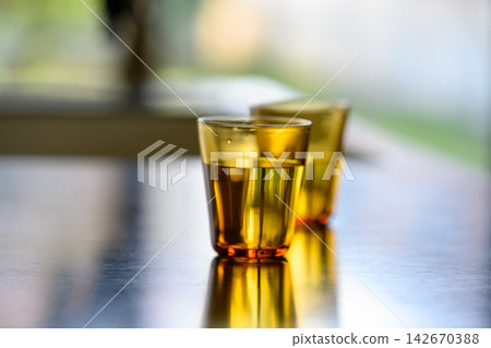 A table lined with amber-colored glasses. A table lined with amber-colored glasses. 142670388