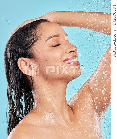 Cleaning hair, water and happy woman in studio for skincare, hygiene or wellness isolated on blue background. Shower, bath and model with eyes closed for dermatology, health and washing for beauty Cleaning hair, water and happy woman in studio for skincare, hygiene or wellness isolated on blue background. Shower, bath and model with eyes closed for dermatology, health and washing for beauty 142670671