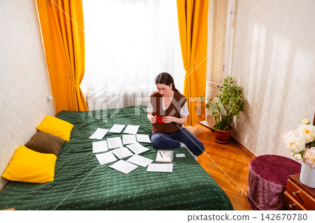 Caucasian woman sitting on bed planning future savings and optimizing household budget. concept of financial intelligence and responsible budgeting. Top view, wide shot Caucasian woman sitting on bed planning future savings and optimizing household budget. concept of financial intelligence and responsible budgeting. Top view, wide shot 142670780