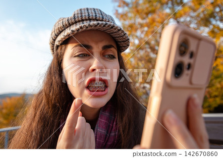Portrait of young woman expressing anger and disbelief after receiving disturbing information on mobile phone. Communication and emotional reaction concept. Portrait of young woman expressing anger and disbelief after receiving disturbing information on mobile phone. Communication and emotional reaction concept. 142670860