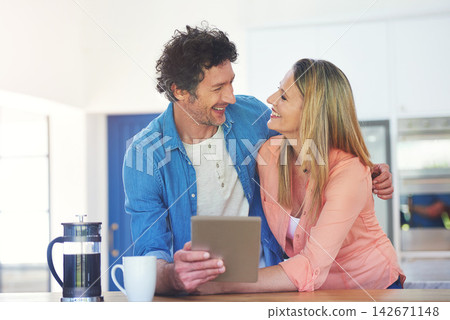 Mature, couple and happy in kitchen with tablet for reading online post, social media scroll or embrace in home. People, hug or laughing with tech app for funny meme, bonding or morning news in house Mature, couple and happy in kitchen with tablet for reading online post, social media scroll or embrace in home. People, hug or laughing with tech app for funny meme, bonding or morning news in house 142671148