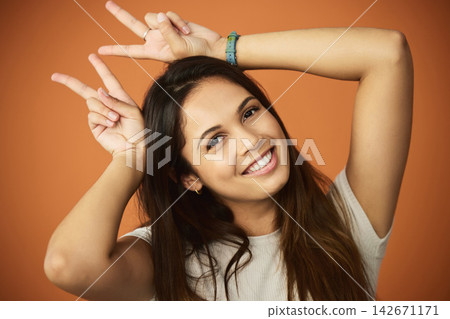 Gen z, woman and bunny ears in studio with emoji for comedy, funny and happy by backdrop. Female person, peace sign and goofy mood by orange background with smile for silly, meme and hand gesture Gen z, woman and bunny ears in studio with emoji for comedy, funny and happy by backdrop. Female person, peace sign and goofy mood by orange background with smile for silly, meme and hand gesture 142671171