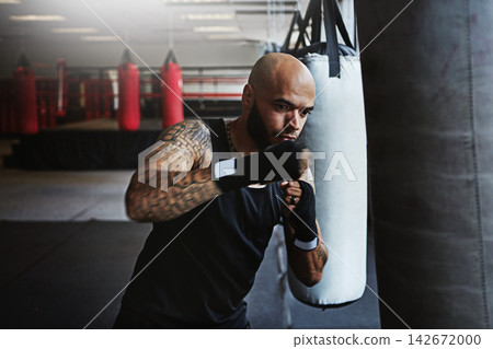 Fitness, punching bag and man in boxing for workout, gym challenge or competition training. Power, muscle and strong champion boxer in exercise with confidence, fight and energy in MMA sports club. Fitness, punching bag and man in boxing for workout, gym challenge or competition training. Power, muscle and strong champion boxer in exercise with confidence, fight and energy in MMA sports club. 142672000