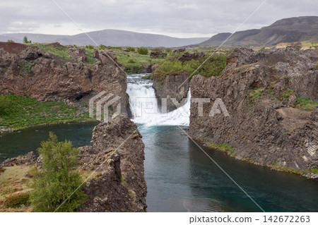 Hjalparfoss waterfall in a broad volcanic mountain landscape in Iceland Hjalparfoss waterfall in a broad volcanic mountain landscape in Iceland 142672263