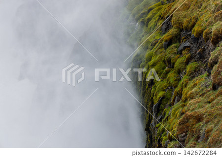 Gullfoss waterfall spray beside a moss-covered canyon wall among volcanic landforms in Iceland Gullfoss waterfall spray beside a moss-covered canyon wall among volcanic landforms in Iceland 142672284