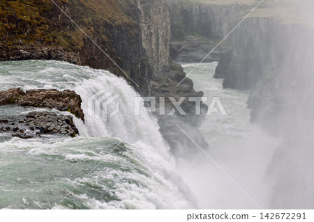Gullfoss waterfall dropping beside columnar basalt cliffs in the Icelandic landscape Gullfoss waterfall dropping beside columnar basalt cliffs in the Icelandic landscape 142672291