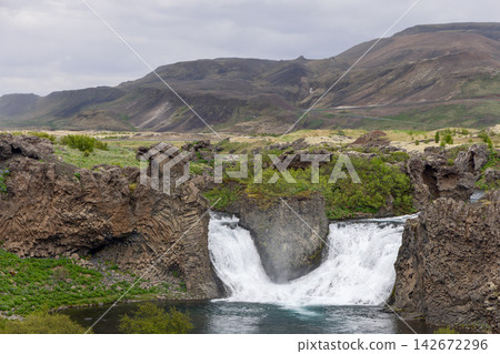 Twin Hjalparfoss waterfall divided by a central volcanic rock in a serene Icelandic landscape Twin Hjalparfoss waterfall divided by a central volcanic rock in a serene Icelandic landscape 142672296
