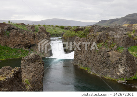 Hjalparfoss waterfall surrounded by lava formations and mountains in Iceland Hjalparfoss waterfall surrounded by lava formations and mountains in Iceland 142672301