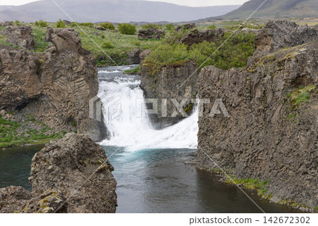 Hjalparfoss waterfall divided by a central basalt block in a wild Icelandic landscape Hjalparfoss waterfall divided by a central basalt block in a wild Icelandic landscape 142672302