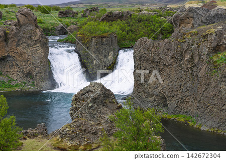 Hjalparfoss waterfall among sculpted basalt formations in wild Icelandic scenery Hjalparfoss waterfall among sculpted basalt formations in wild Icelandic scenery 142672304