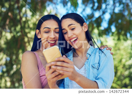 Women, friends and phone in park with laugh for funny meme, video or notification on social media. Girl, students and smartphone for reading, happy and watch live stream for comic story on mobile app Women, friends and phone in park with laugh for funny meme, video or notification on social media. Girl, students and smartphone for reading, happy and watch live stream for comic story on mobile app 142672344