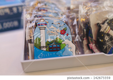 Tourist gifts and Korean souvenirs from Busan, South Korea, toys and figurines, fridge magnets and key ring keychain, key fobs and postcards with symbols of Busan in a local gift vendor shop market Tourist gifts and Korean souvenirs from Busan, South Korea, toys and figurines, fridge magnets and key ring keychain, key fobs and postcards with symbols of Busan in a local gift vendor shop market 142673359