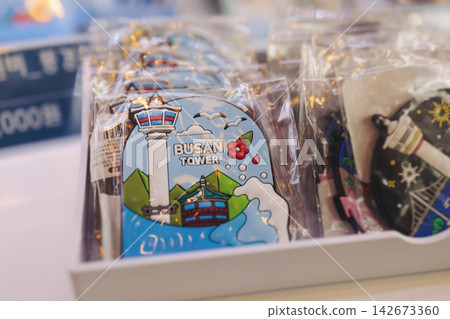 Tourist gifts and Korean souvenirs from Busan, South Korea, toys and figurines, fridge magnets and key ring keychain, key fobs and postcards with symbols of Busan in a local gift vendor shop market Tourist gifts and Korean souvenirs from Busan, South Korea, toys and figurines, fridge magnets and key ring keychain, key fobs and postcards with symbols of Busan in a local gift vendor shop market 142673360