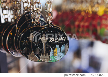 Tourist gifts and Korean souvenirs from Busan, South Korea, toys and figurines, fridge magnets and key ring keychain, key fobs and postcards with symbols of Busan in a local gift vendor shop market Tourist gifts and Korean souvenirs from Busan, South Korea, toys and figurines, fridge magnets and key ring keychain, key fobs and postcards with symbols of Busan in a local gift vendor shop market 142673659