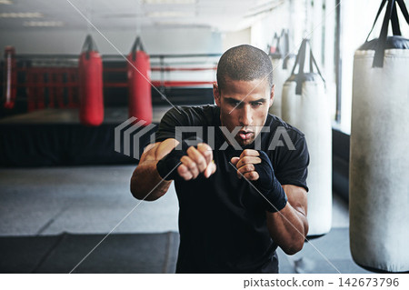 Sports, punching and man in gym for exercise, boxing challenge or competition training. Power, muscle and champion boxer at workout with confidence, fight and energy in MMA fitness club with gloves. Sports, punching and man in gym for exercise, boxing challenge or competition training. Power, muscle and champion boxer at workout with confidence, fight and energy in MMA fitness club with gloves. 142673796