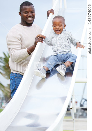 Father, boy and slide at playground, together and excited for playing, bonding and care in summer. Man, child and happy black family at park for games, love and vacation with holding hands for safety Father, boy and slide at playground, together and excited for playing, bonding and care in summer. Man, child and happy black family at park for games, love and vacation with holding hands for safety 142674006