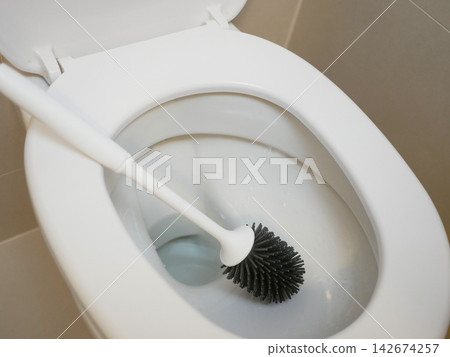 White toilet bowl with a toilet brush in a clean modern bathroom, representing household cleaning, hygiene, sanitation, restroom maintenance and everyday home care. White toilet bowl with a toilet brush in a clean modern bathroom, representing household cleaning, hygiene, sanitation, restroom maintenance and everyday home care. 142674257