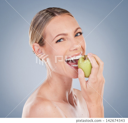 Skincare, apple and portrait of happy woman in studio for natural glow, facial treatment or wellness on gray background. Eating, fruit and model with bite for nutrition, vitamin c or body detox Skincare, apple and portrait of happy woman in studio for natural glow, facial treatment or wellness on gray background. Eating, fruit and model with bite for nutrition, vitamin c or body detox 142674343