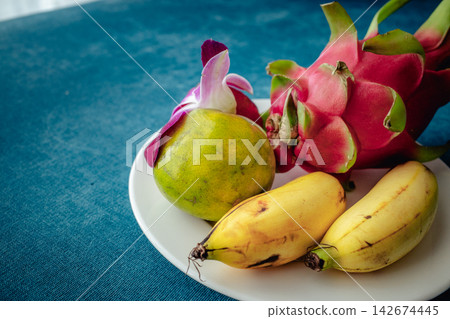 Beautifully arranged on a white plate are tropical fruits: dragon fruit, banana, lime, and orchid. Beautifully arranged on a white plate are tropical fruits: dragon fruit, banana, lime, and orchid. 142674445