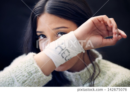 Woman, depression and crying for help, suicide and mental health support with self harm idea in portrait. Girl, bandage and wrist injury or accident for pain, trauma and anxiety with frustrated tears Woman, depression and crying for help, suicide and mental health support with self harm idea in portrait. Girl, bandage and wrist injury or accident for pain, trauma and anxiety with frustrated tears 142675076
