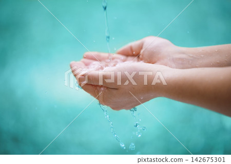 Person, hands and water with drops for natural hydration, hygiene or sustainability on a blue background. Closeup of wet consumer with splash, liquid element or fresh mineral for care, hope or nature Person, hands and water with drops for natural hydration, hygiene or sustainability on a blue background. Closeup of wet consumer with splash, liquid element or fresh mineral for care, hope or nature 142675301