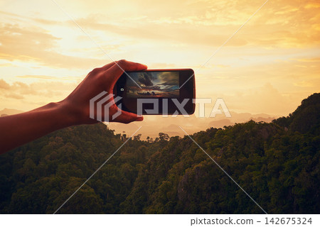 Sunset, nature and hand with cellphone for picture on vacation, adventure or weekend trip in Brazil. Evening, mobile and person with phone for photography of outdoor dawn sky on holiday for travel. Sunset, nature and hand with cellphone for picture on vacation, adventure or weekend trip in Brazil. Evening, mobile and person with phone for photography of outdoor dawn sky on holiday for travel. 142675324