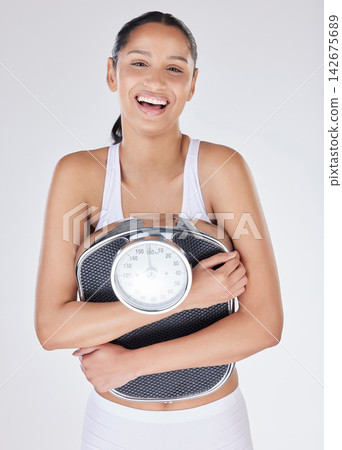Girl, portrait and scale in studio for weight loss, smile and excited for results of diet or detox. Female person, laugh and happy for calories burned progress or goals, wellness and white background Girl, portrait and scale in studio for weight loss, smile and excited for results of diet or detox. Female person, laugh and happy for calories burned progress or goals, wellness and white background 142675689