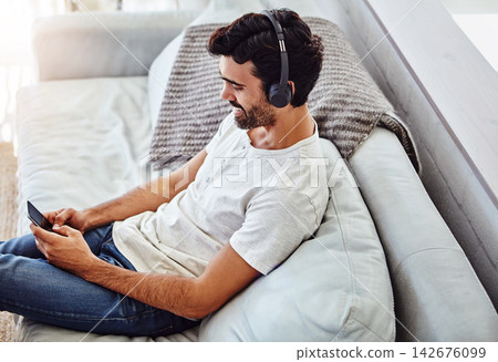 Home, man and cellphone with headphones on couch for listening to music, radio and networking. Living room, male chatter and mobile app for streaming podcast, online games and social media to relax Home, man and cellphone with headphones on couch for listening to music, radio and networking. Living room, male chatter and mobile app for streaming podcast, online games and social media to relax 142676099