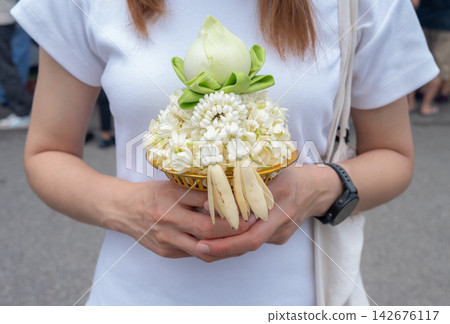 Woman holding jasmine flower garlands to the revered Luang Pho Tan Jai (Buddha of Success) statue at Wat Phra That Doi Kham in Chiang Mai to make or fulfill wishes for luck, wealth, and career success Woman holding jasmine flower garlands to the revered Luang Pho Tan Jai (Buddha of Success) statue at Wat Phra That Doi Kham in Chiang Mai to make or fulfill wishes for luck, wealth, and career success 142676117