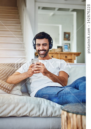 Man, headphones and phone or laughing for video in home with funny social media post or comedy movie on mobile app. Person, smartphone and relax for listening to audio, sound and subscription on sofa Man, headphones and phone or laughing for video in home with funny social media post or comedy movie on mobile app. Person, smartphone and relax for listening to audio, sound and subscription on sofa 142676228