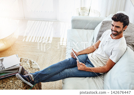 Top view, man and relax with tablet in home for internet browsing, social media and comfortable on sofa. Person, happy and digital tech on couch in living room for online information or weekend break Top view, man and relax with tablet in home for internet browsing, social media and comfortable on sofa. Person, happy and digital tech on couch in living room for online information or weekend break 142676447