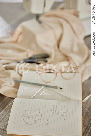 Sketch, book and design for fashion in workshop for art, handcraft and creativity for small business. Drawing, tools and sewing machine for designer, seamstress or tailor with measurements or fabric Sketch, book and design for fashion in workshop for art, handcraft and creativity for small business. Drawing, tools and sewing machine for designer, seamstress or tailor with measurements or fabric 142676460