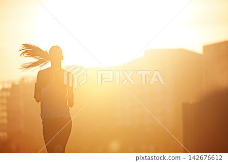 Woman, running and silhouette in sunrise for exercise with fitness, development or speed by buildings in city. Girl, person and athlete with training, workout and outdoor on metro road by skyscraper Woman, running and silhouette in sunrise for exercise with fitness, development or speed by buildings in city. Girl, person and athlete with training, workout and outdoor on metro road by skyscraper 142676612